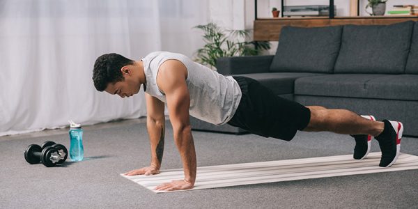 Man doing push ups in sportswear on fitness mat